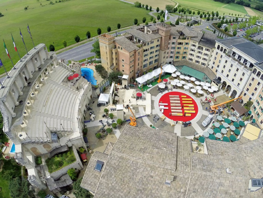Luftaufnahme eines großen historischen Amphitheaterkomplexes, eingebettet in ein umgebendes Grüngebiet mit mehreren Gebäuden.