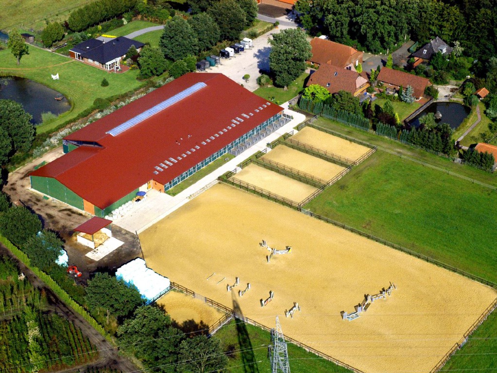 Luftaufnahme eines großen Reit- und Stallkomplexes mit Trainingsgelände und ländlicher Umgebung.