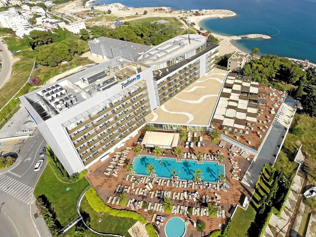 Luftaufnahme eines großen, luxuriösen Hotelresorts mit umfangreicher Poolanlage und Blick auf das Meer.